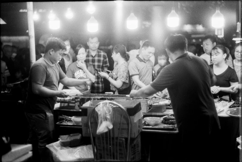 several men at a bar in a restaurant standing around a table with several plates on it