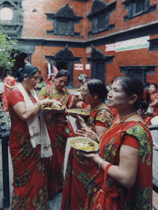 women in brightly colored clothes eating food while people watching