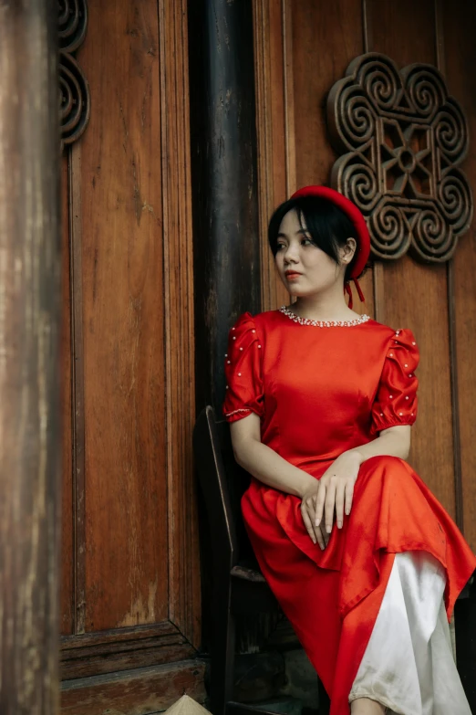 a woman in red sitting down wearing a red hat