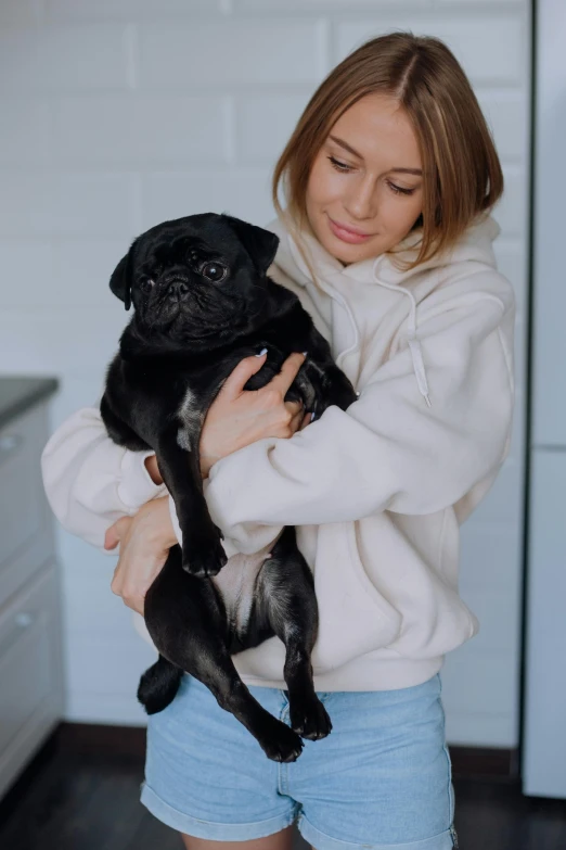 a woman holding a black dog in her arms