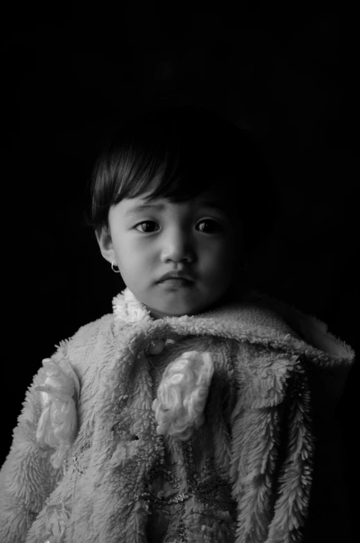 a little boy in a fur jacket on a black background