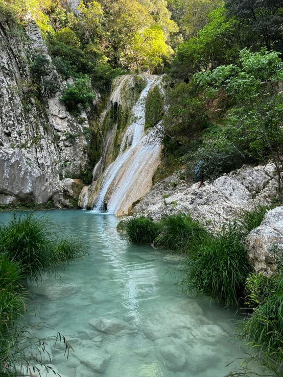 a man in the water at the base of a waterfall