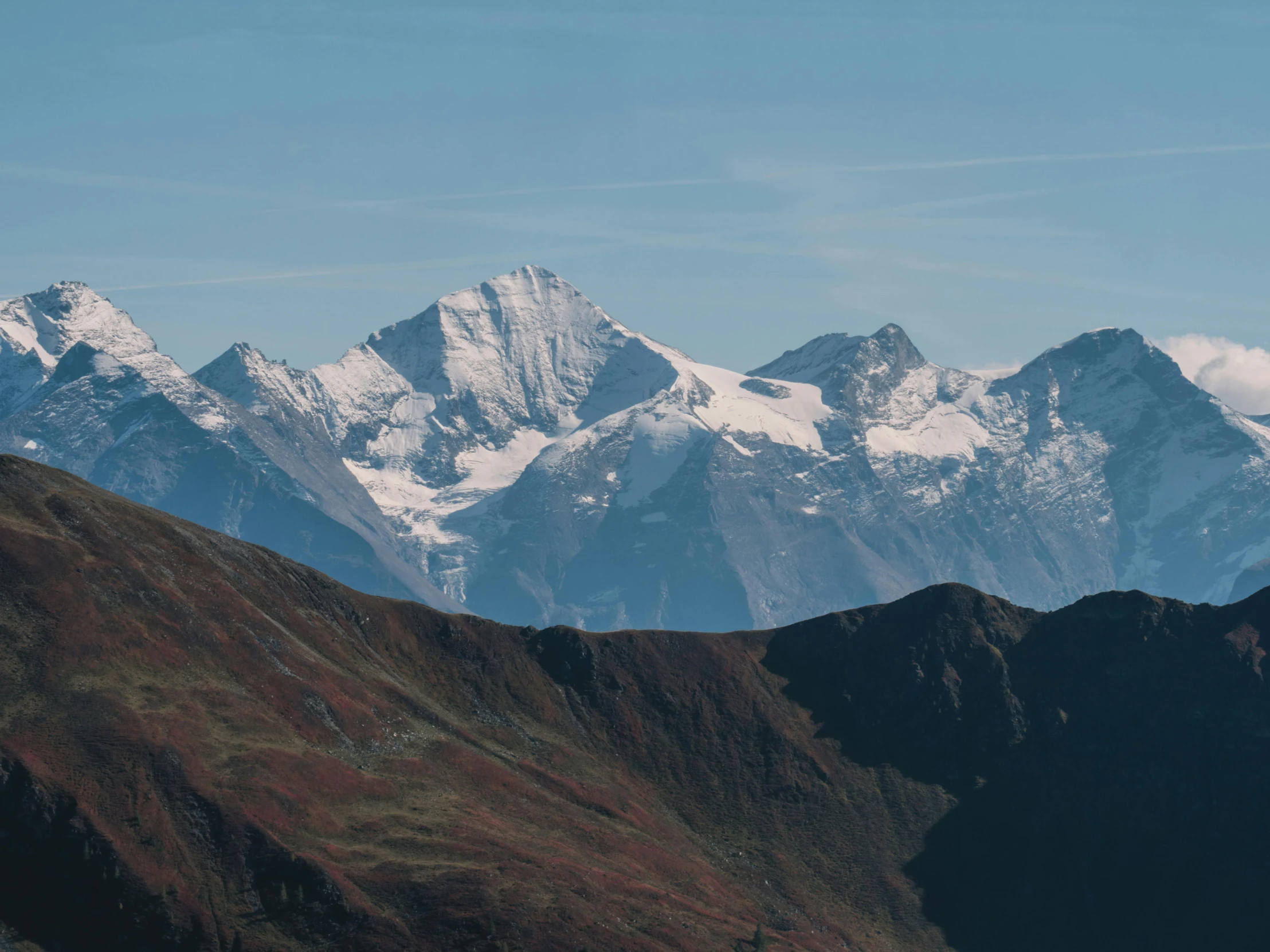 several mountains covered in snow under a blue sky