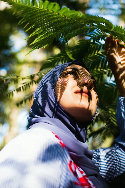 woman in headscarf looking up from the trees