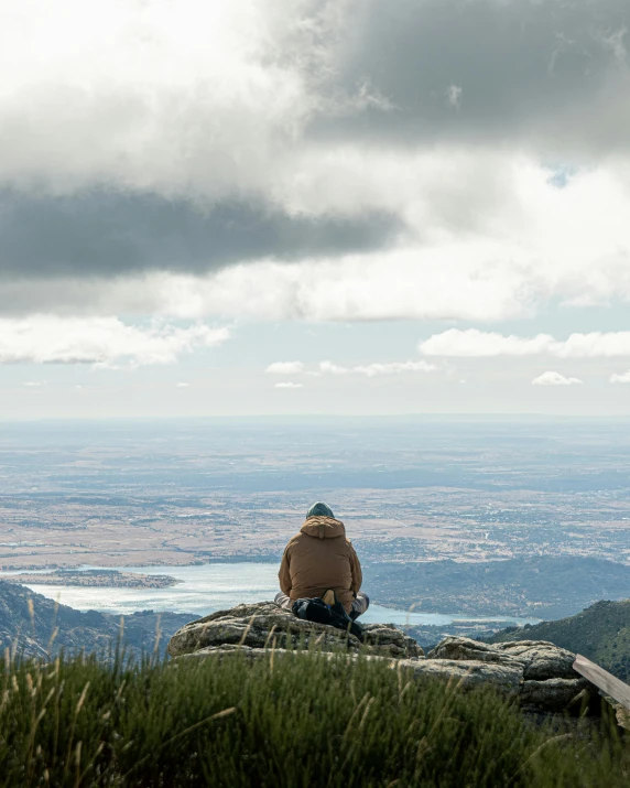 a man is sitting on a rock and looking out into the water