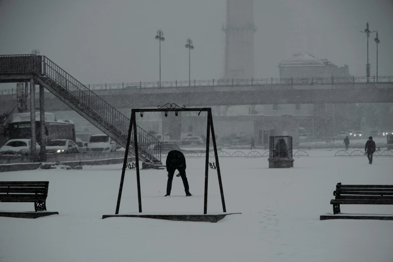 a man is on swings with a snowy cityscape