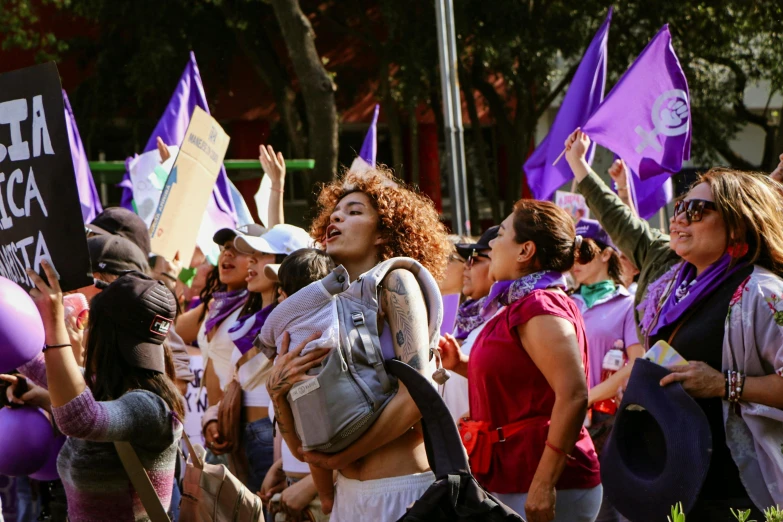 people with purple hats and banners, all holding up their hand gestures