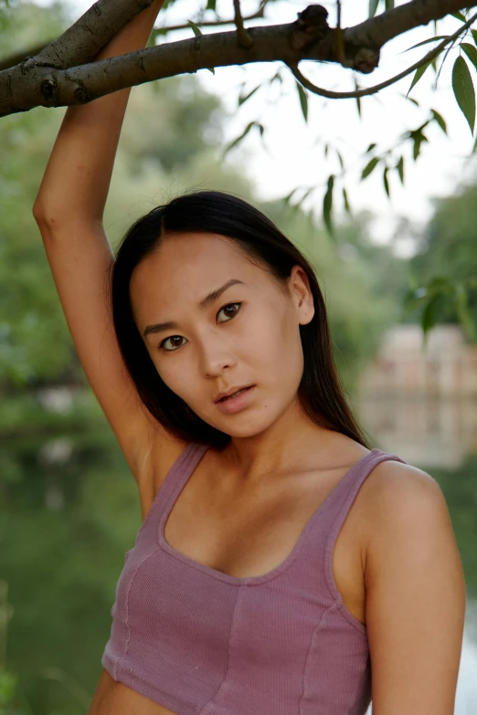 a woman wearing a purple top and posing in front of trees