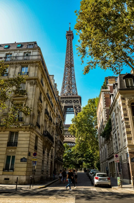 a group of people walking through the streets in front of the eiffel tower