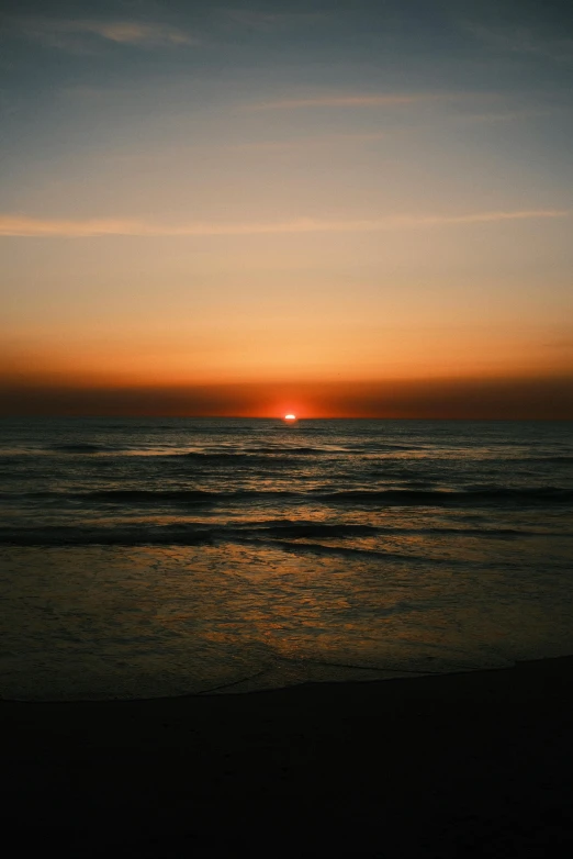 the sun sets over the horizon of the beach