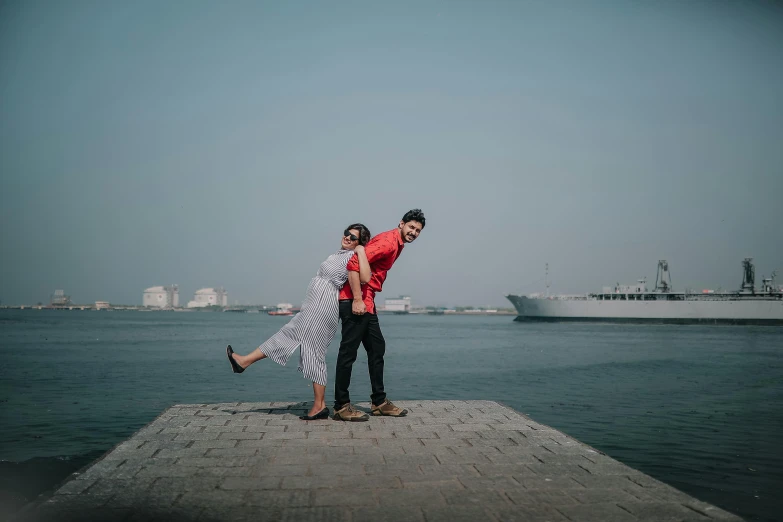 two people pose in front of a large ship