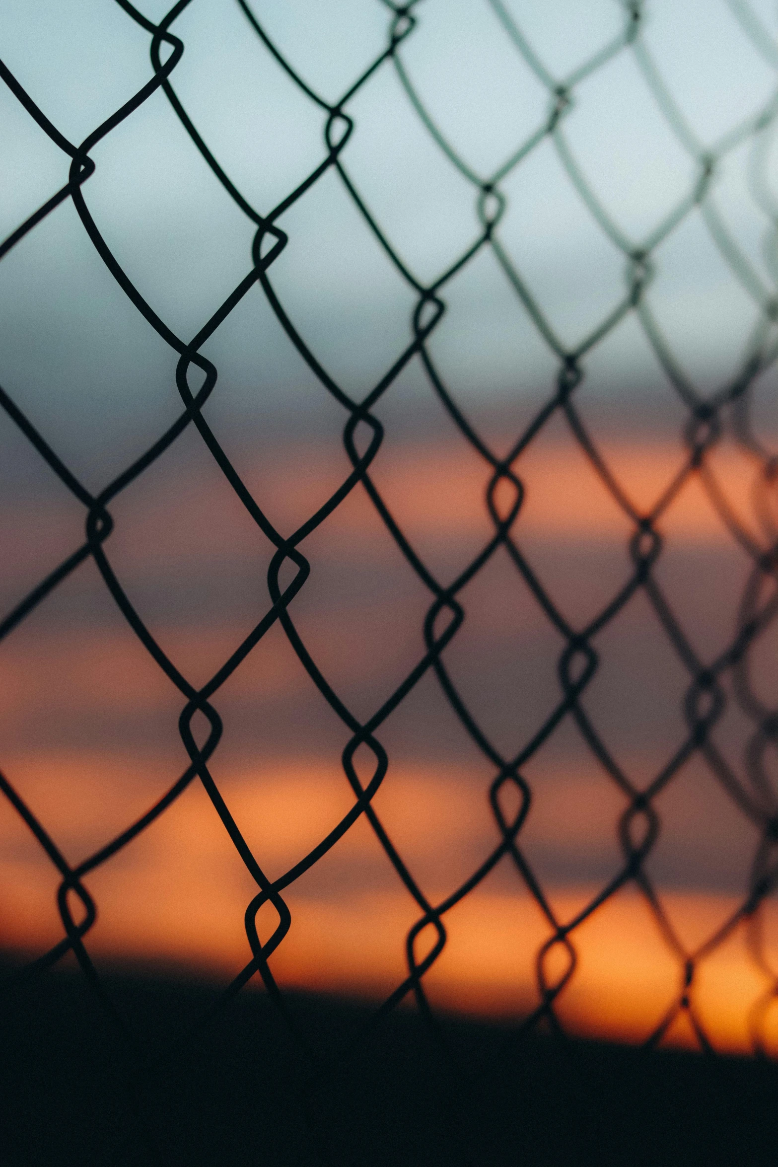 the view through a chain link fence at sunset