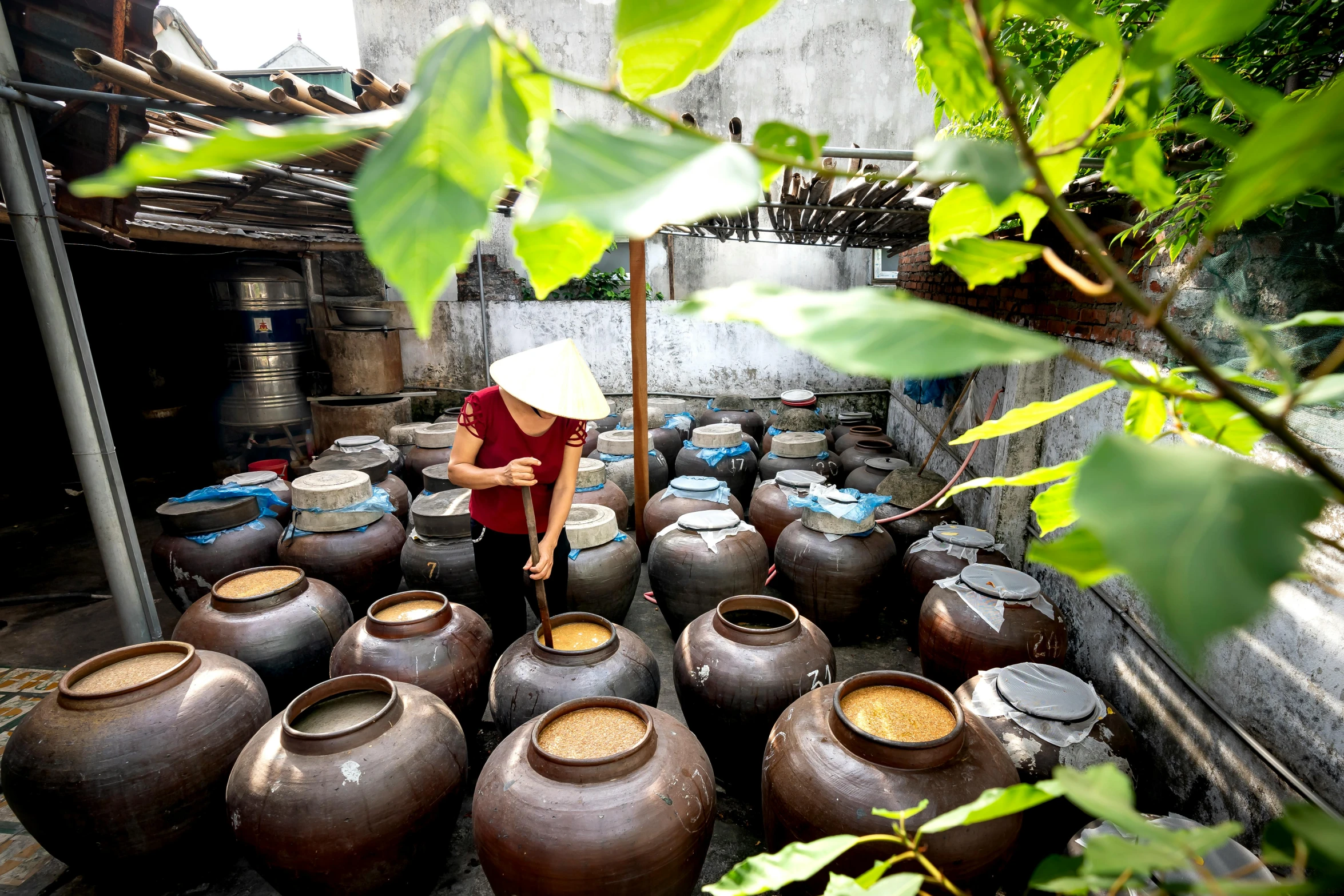 a woman holding an umbrella stands in front of many large jugs