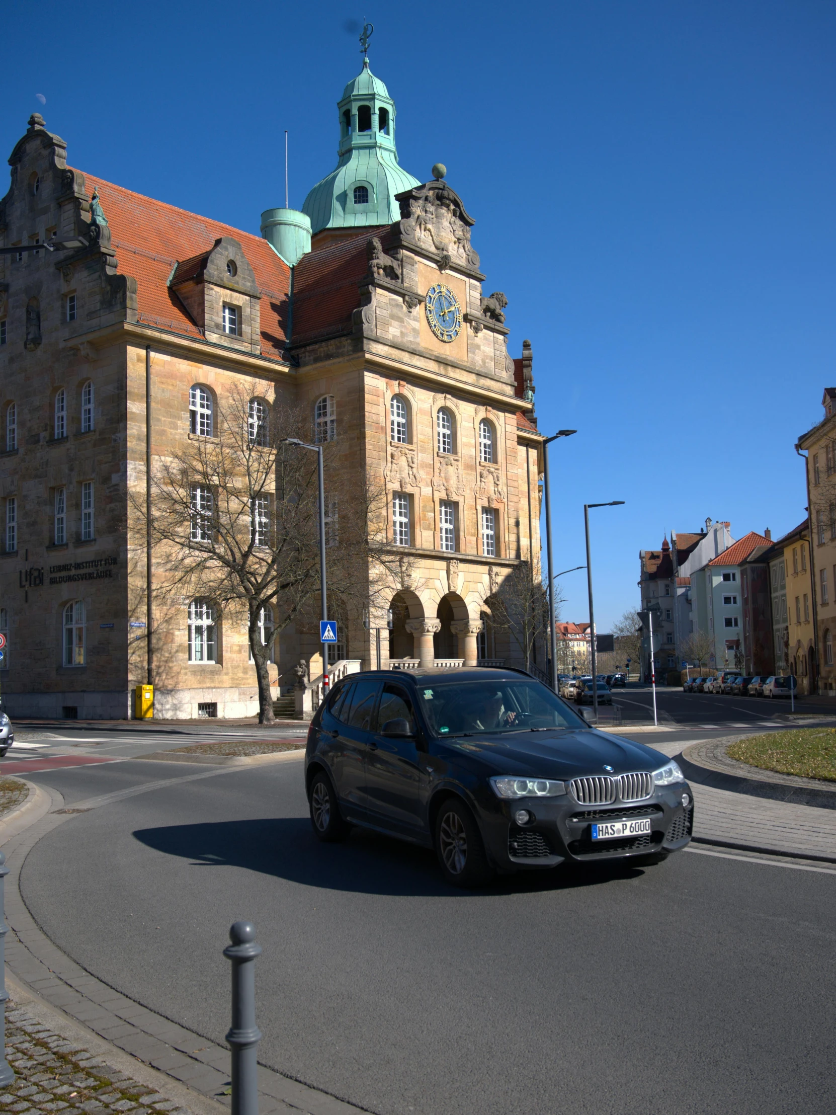 an old castle sits in the middle of a street with a car driving in front