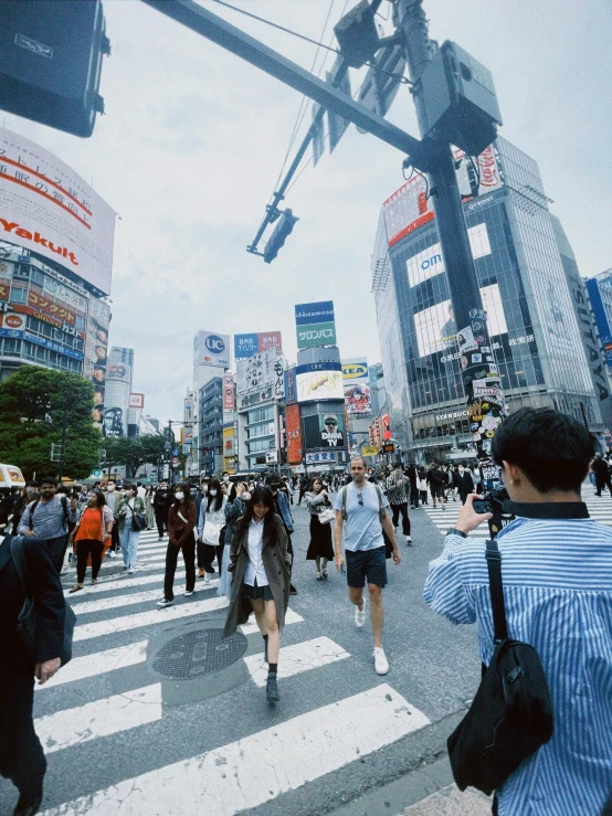 people crossing a busy city intersection with tall buildings in the background