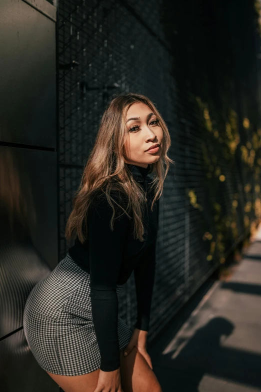 a women is leaning on a wall posing for the camera