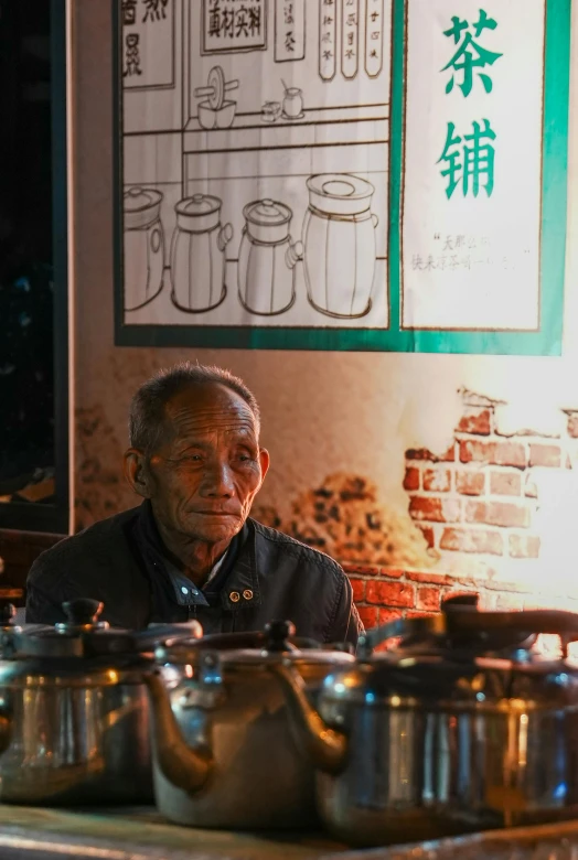 a man wearing a black shirt next to pots on a table