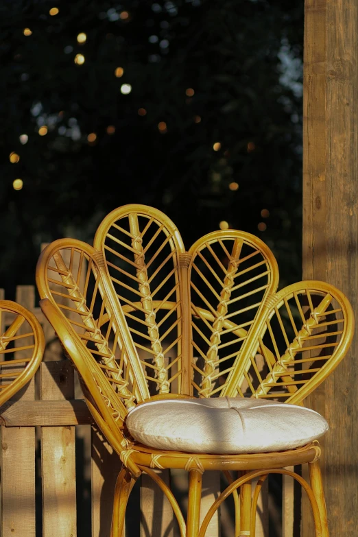 an old chair is painted gold and is next to a wooden fence