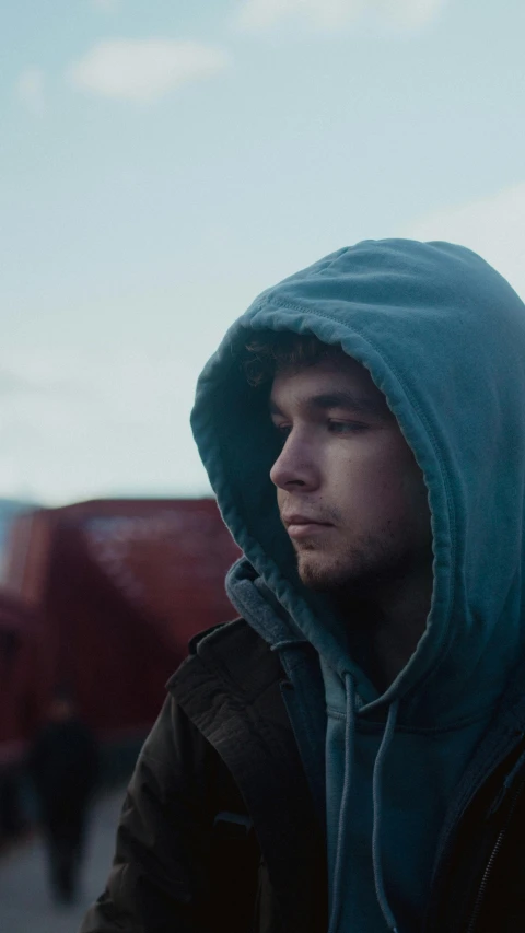 a man with a hooded jacket on in a parking lot