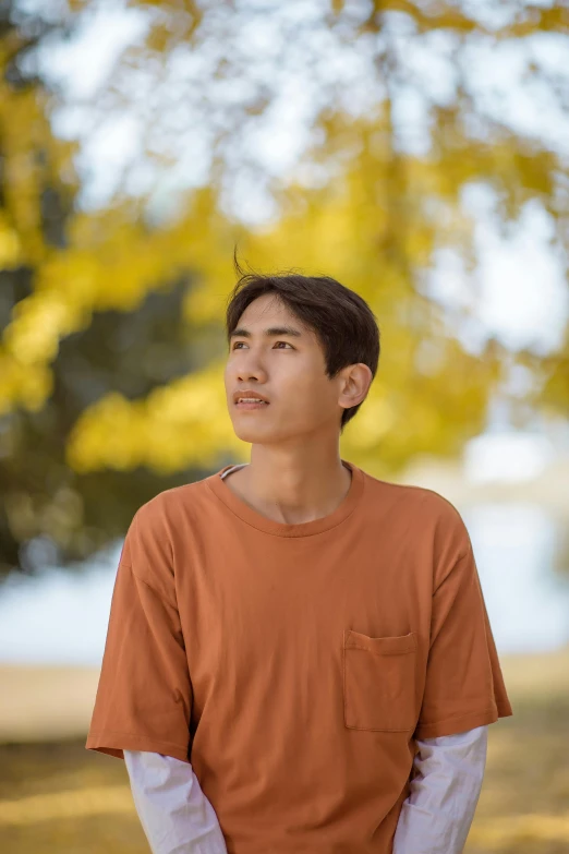 a young man standing under a tree looking away