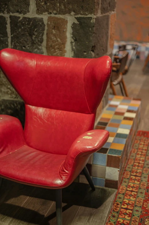 a red chair in front of a brick wall