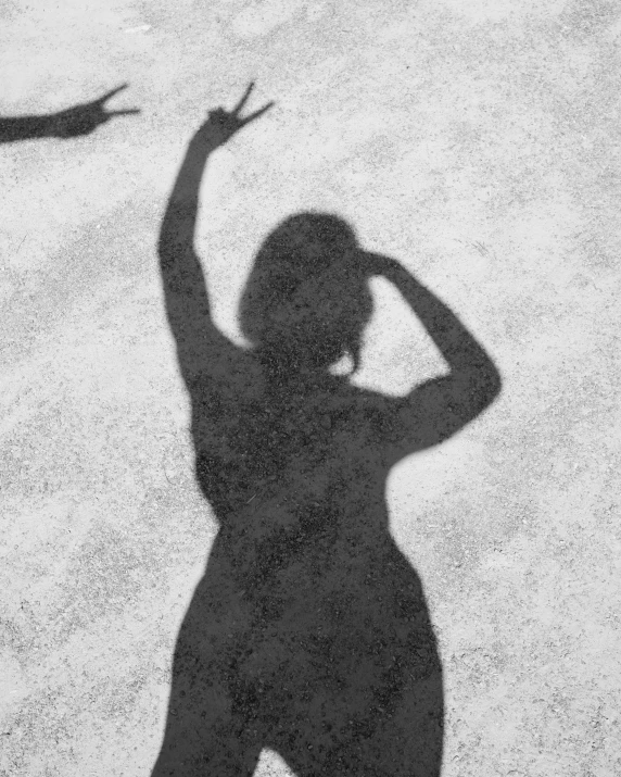 a black and white po shows a woman's shadow with hands raised
