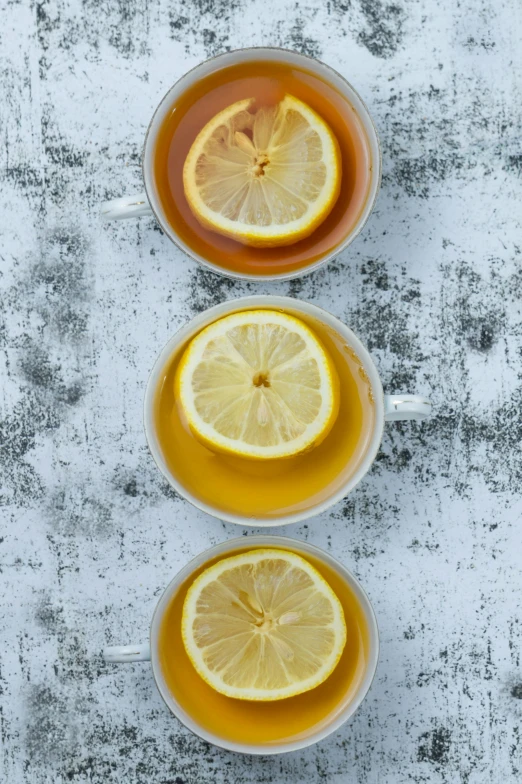 three cups of tea with lemon halves and ice