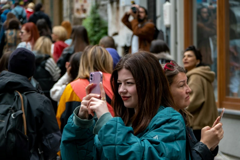 two girls are holding up their cell phones