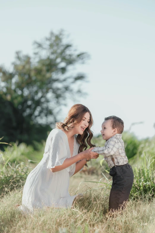 an adorable little boy holds his mom's hand while in a field