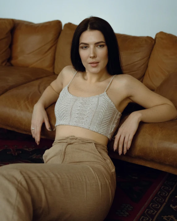 a young woman is posing on a brown sofa