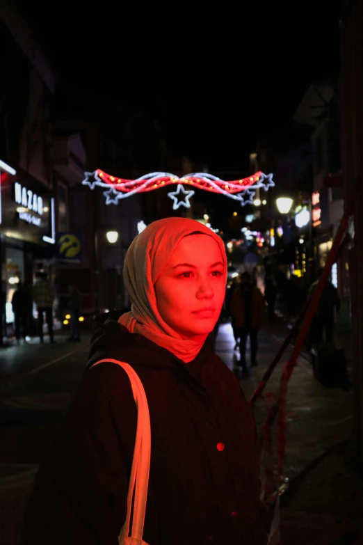 a woman is on the street at night with christmas lights