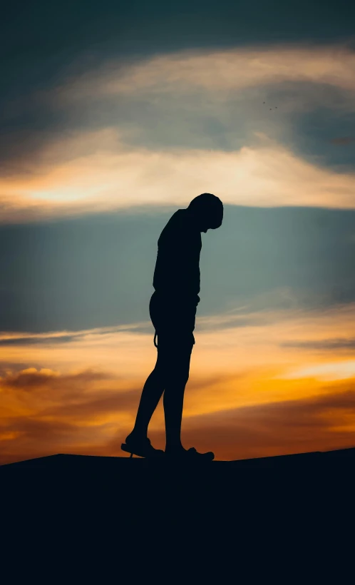 a person standing on the sand at sunset