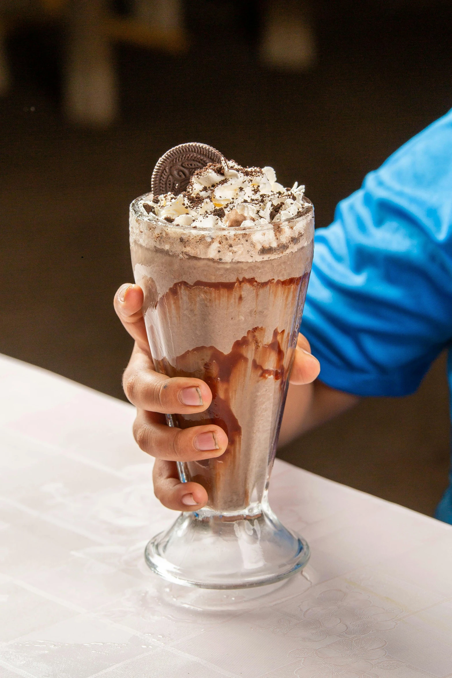 a person holding up a chocolate milkshake