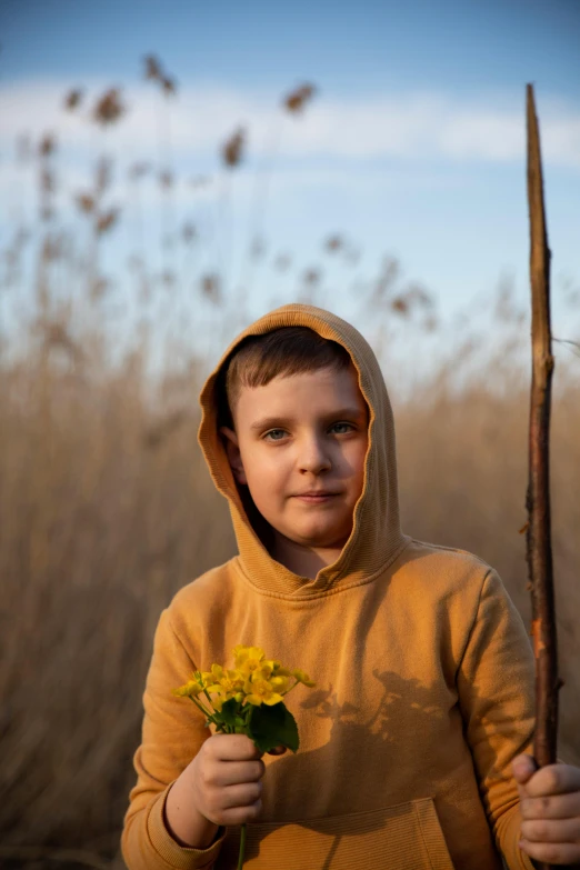 a little boy holding flowers wearing a hoody