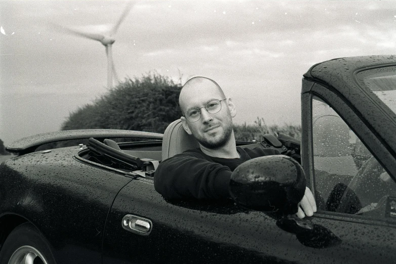 a man sits on the hood of a car