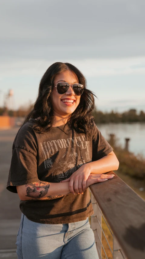 a smiling woman standing over a wooden fence