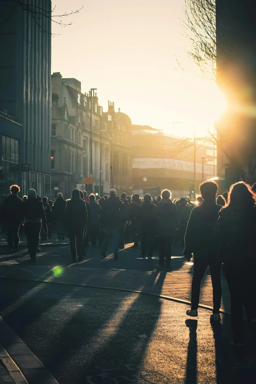 people are standing on the side walk as the sun sets