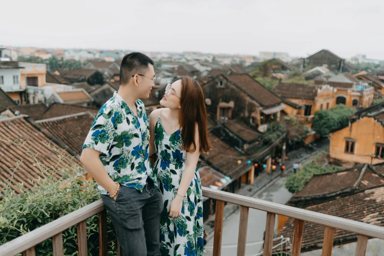 a man and woman standing on a wooden balcony next to an old building