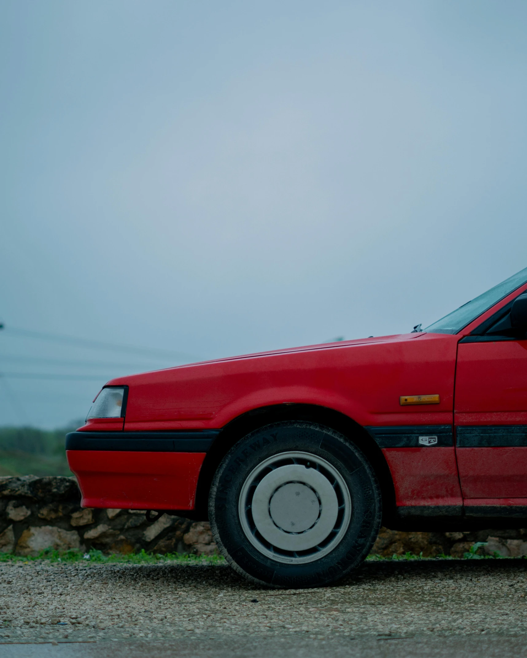 a red car sitting on top of a rock wall