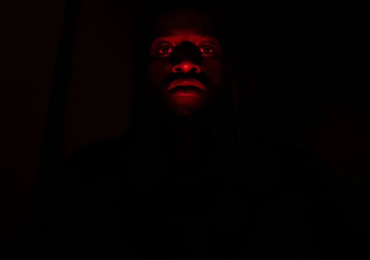 a man is standing in the dark with red eyes