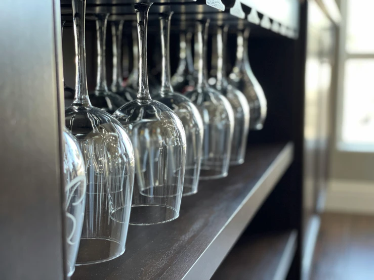 a rack full of clear wine glasses hanging on a wall