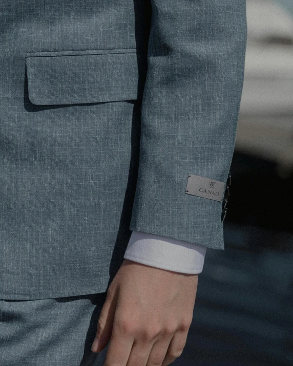 a person in a gray suit standing with their hands together