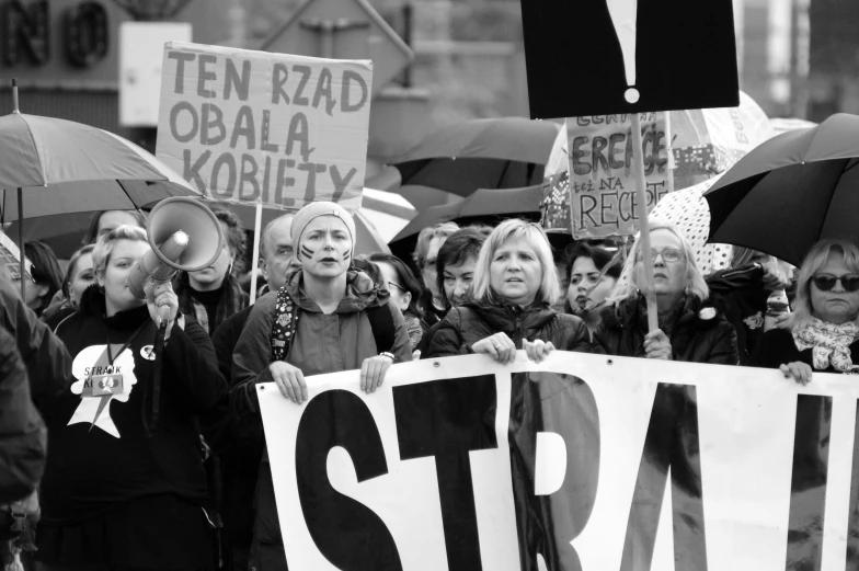 some people are holding up signs with an umbrella