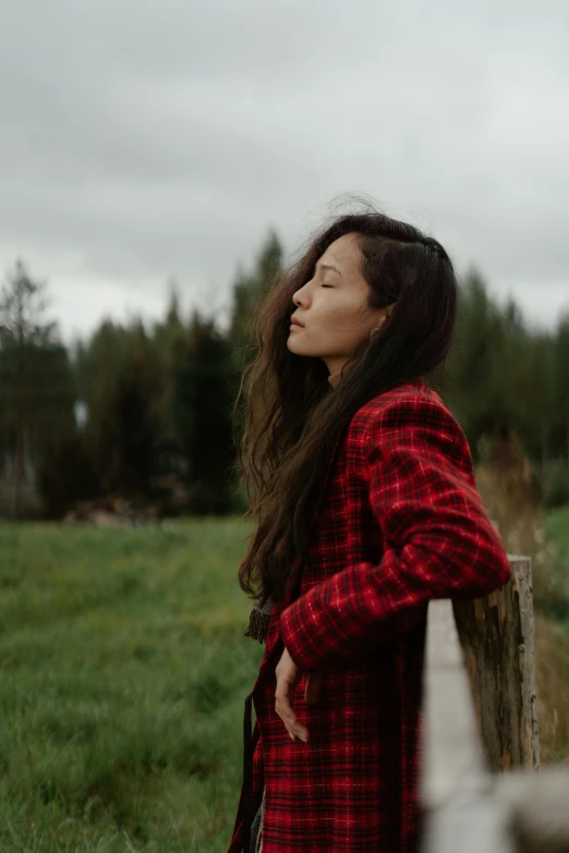 a woman standing with her head resting on a fence