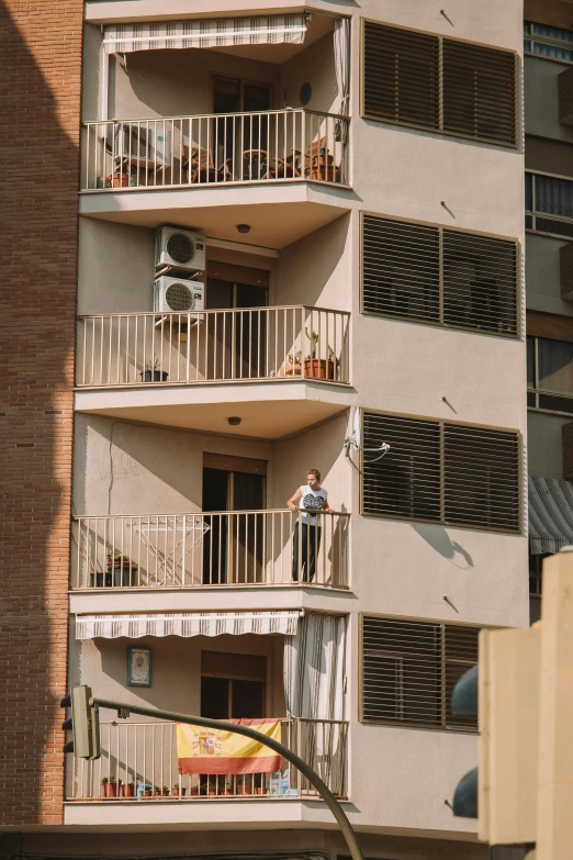 a building with three balconies on the top and a man sitting on the upper floor