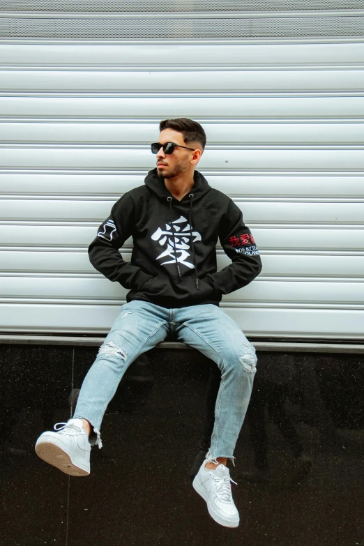 man in sunglasses and a hoodie sitting on the floor