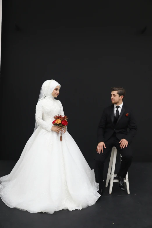 man and woman sit wearing wedding gowns on chairs