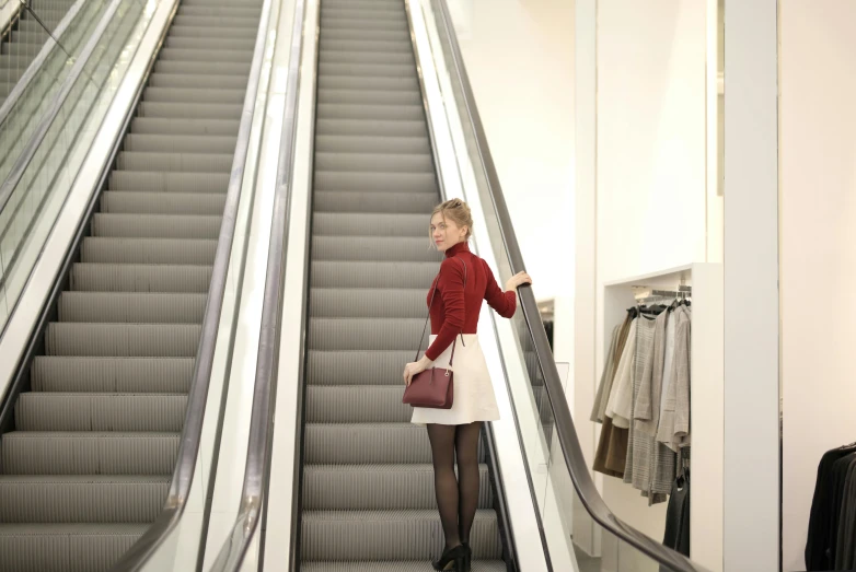 a woman is going down an escalator on her luggage