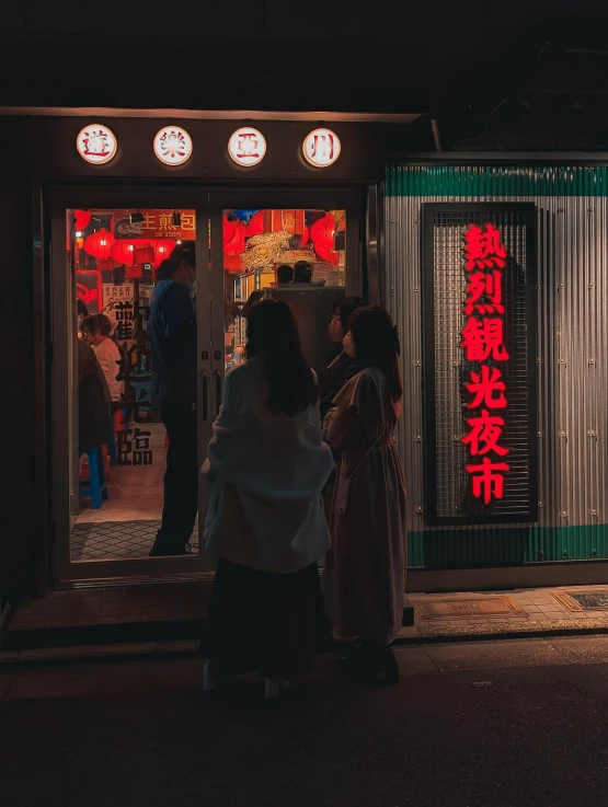 a woman is standing outside a store window at night