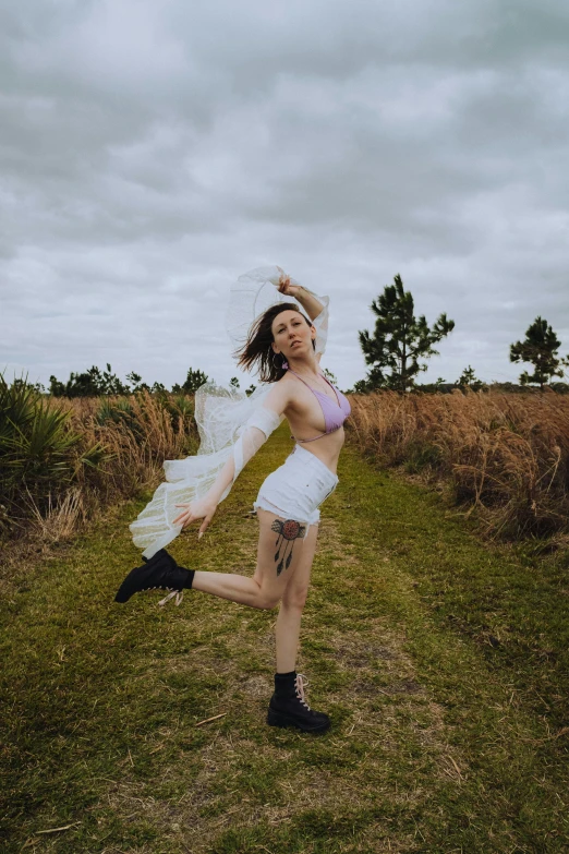 young lady dancing in a field posing for a po